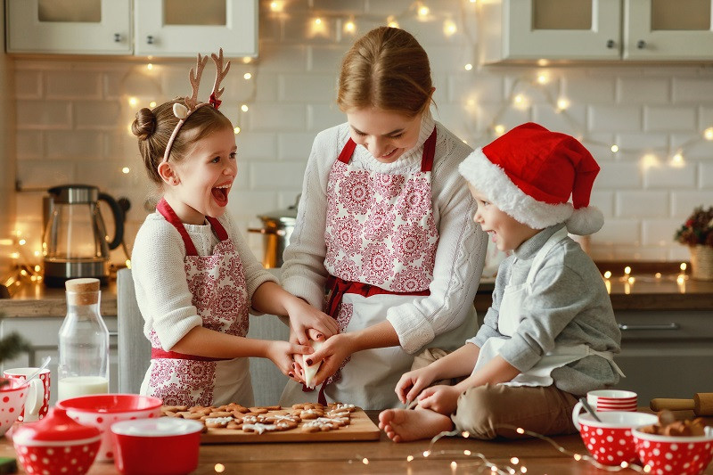 Matka ve vánoční zástěře peče s dětmi cukroví